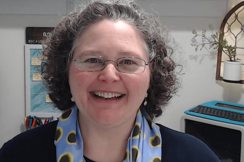 Shannon Medisky wearing a dark shirt and a polka dot scarf smiling